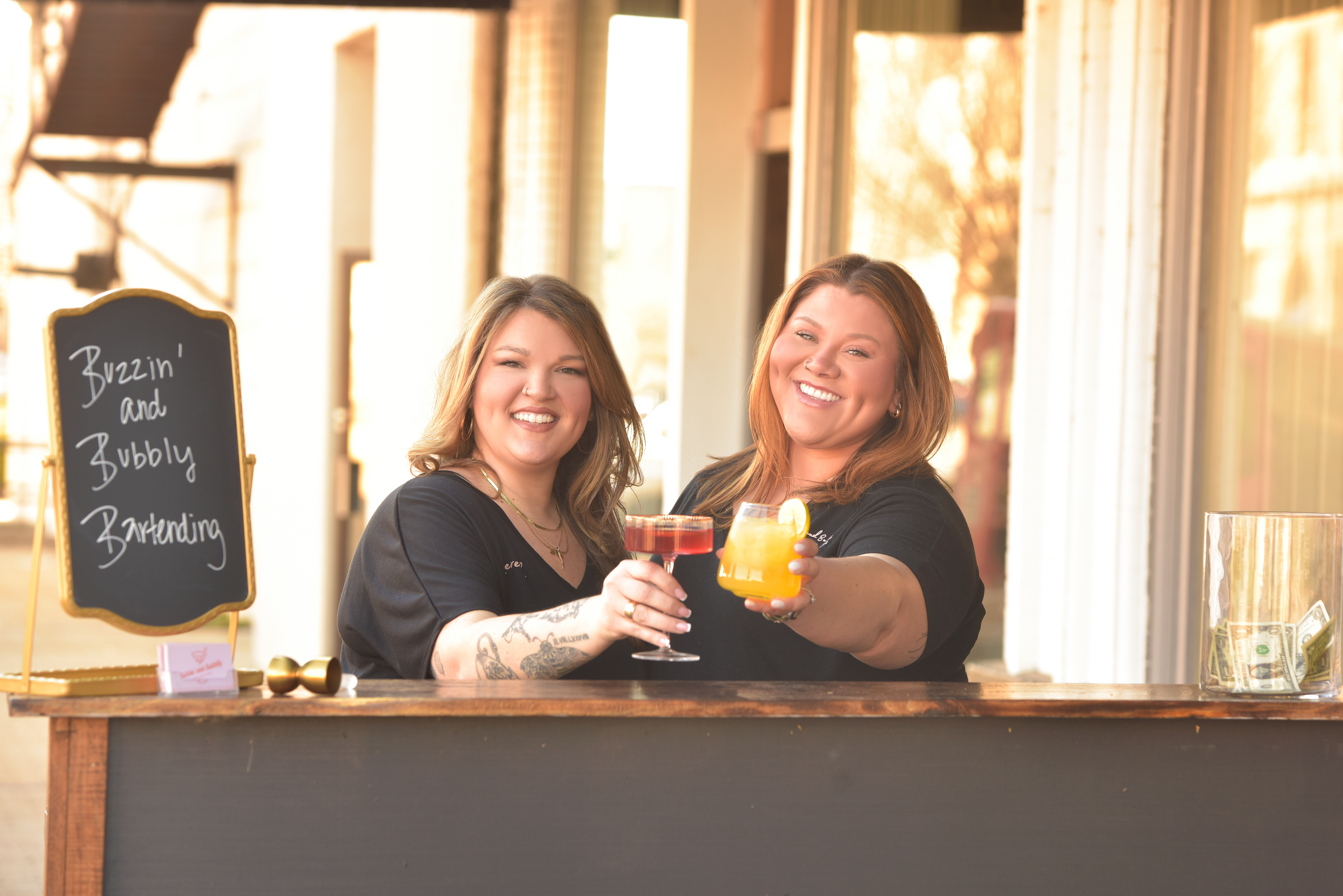 bartenders holding cocktails behind bar